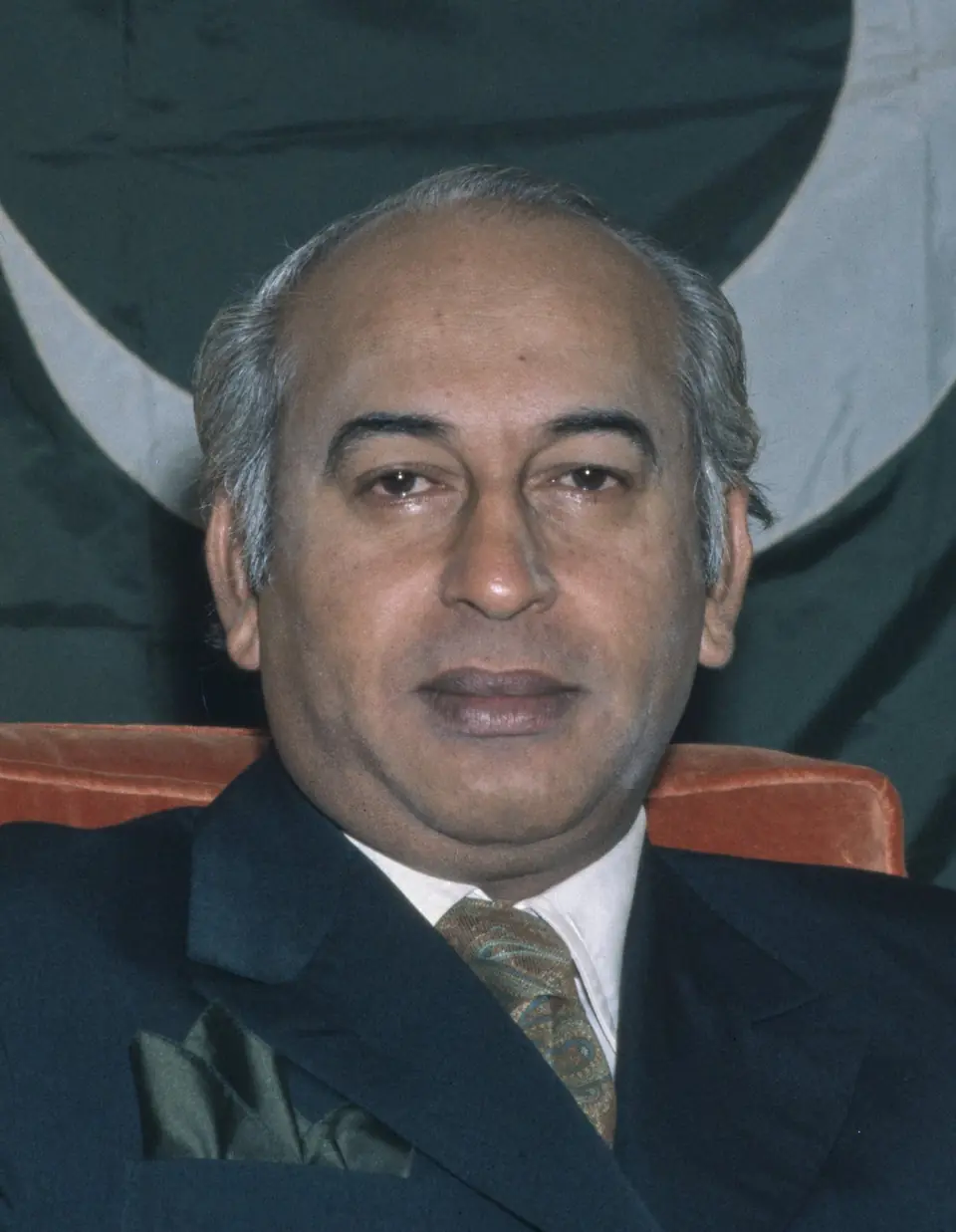 Zulfikar Ali Bhutto, former Prime Minister of Pakistan, in a portrait from the 1970s with a Pakistani flag behind him