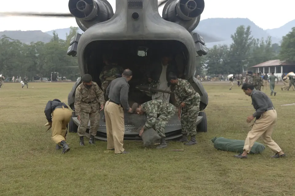 Pakistani soldiers and local police unload relief supplies from a US Army CH-47 Chinook helicopter at a landing zone in Muzaffarabad, 12 October 2005