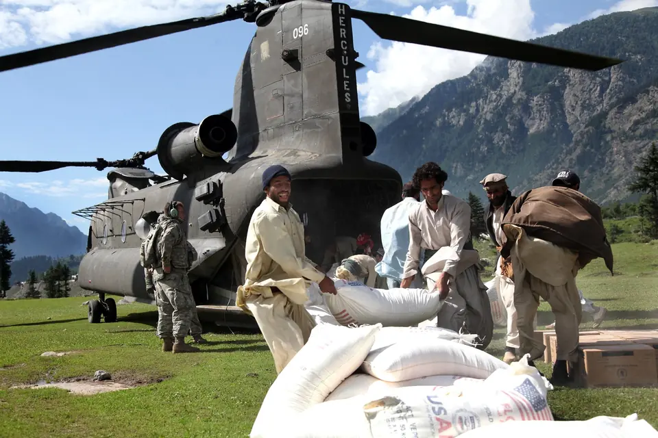 Pakistani men unload bags of flour from a US Army CH-47 Chinook helicopter delivering flood relief in the Swat Valley, 11 August 2010